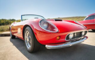 A red sports car is driving down the road needing a pre-purchase inspection