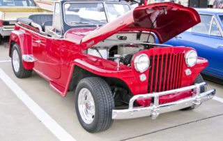 A red jeep parked in the parking lot with other vehicles needing a pre-purchase inspection