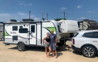 A couple standing in front of their camper after an RV inspection service